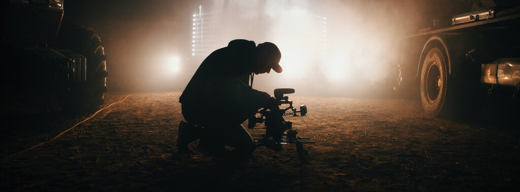 A man operates a video camera against a backlight. Photograph by Jon Flobrant.